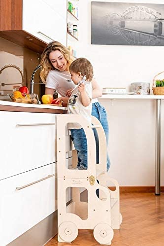 niño en la cocina en su torre de aprendizaje Montessori